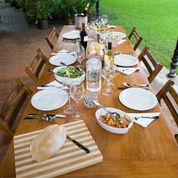 A long outdoor dining table set with a lunch spread for six places