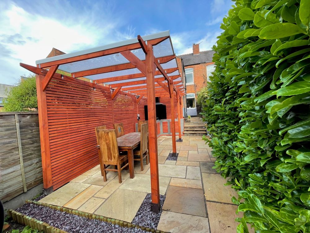 An example of a pergola with a kitchen area under it with seating.